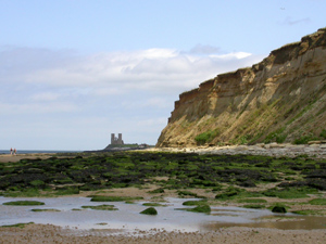 The foreshore and cliffs east of Herne Bay with the towers of St Mary's church, Reculver in the background
